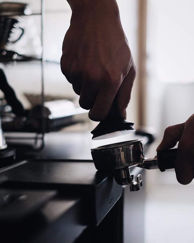 barista tamps coffee for the espresso machine