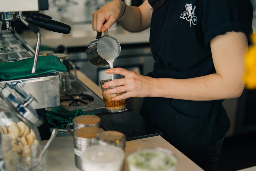 A barista pours steamed milk for a latte